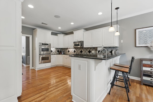 15 Challain Cv, Little Rock, AR 72223 - kitchen with appliances with stainless steel finishes, crown molding, dark countertops, a peninsula, and a breakfast bar area