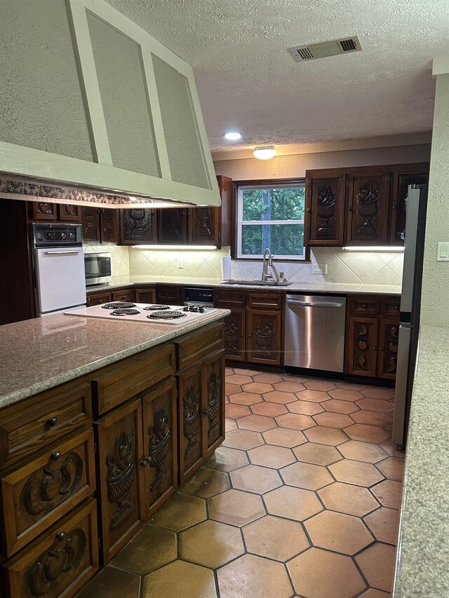 18 Riviera Dr, Conway, AR 72034 - kitchen with appliances with stainless steel finishes, a sink, decorative backsplash, a textured ceiling, and extractor fan