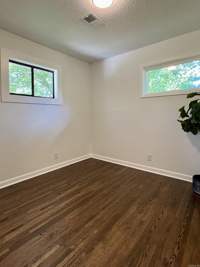 506 W Clinton St, Heber Springs, AR 72543 - unfurnished room with dark wood finished floors, plenty of natural light, baseboards, and a textured ceiling
