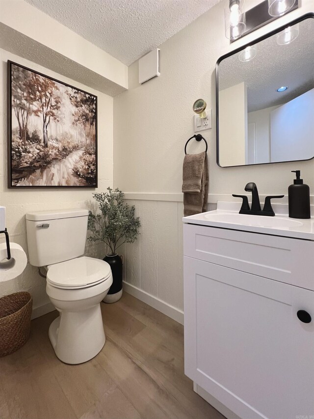 506 W Clinton St, Heber Springs, AR 72543 - bathroom featuring a textured ceiling, wainscoting, wood finished floors, vanity, and toilet