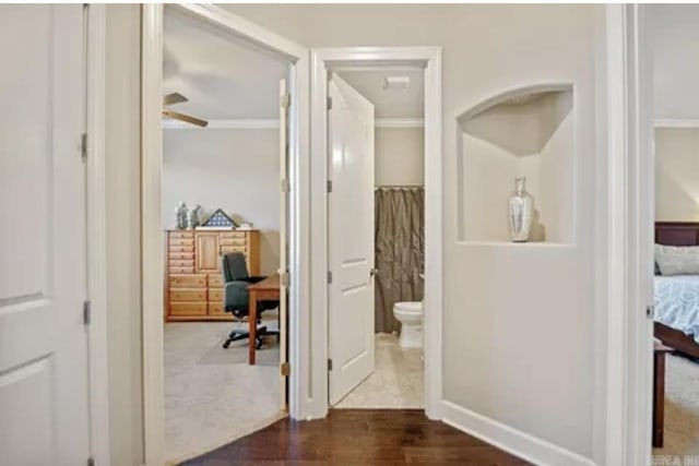 bathroom featuring toilet, wood finished floors, crown molding, ensuite bathroom, and baseboards