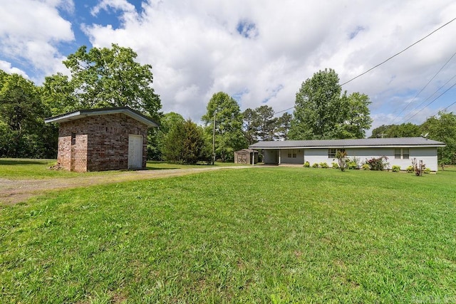 135 Cress Ln, Clinton, AR 72031 - view of grassy yard with dirt driveway, a storage unit, an outdoor structure, and an attached carport