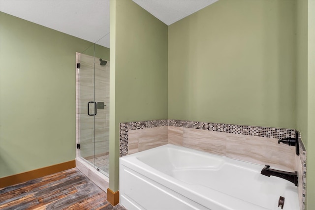 17259 Reynolds Rd, Harrisburg, AR 72432 - bathroom with a shower stall, a bath, wood finished floors, and baseboards