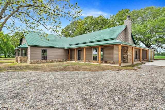 17259 Reynolds Rd, Harrisburg, AR 72432 - view of front of house with concrete driveway, an attached garage, metal roof, stone siding, and a chimney