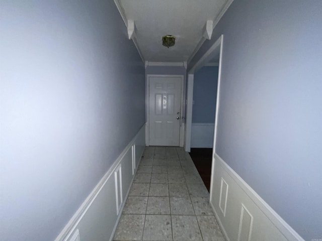 hallway featuring ornamental molding and light tile patterned floors