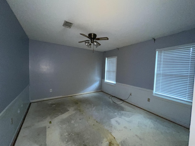 empty room featuring concrete floors, ceiling fan, and baseboards