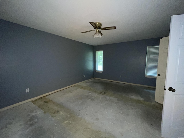 unfurnished room featuring a ceiling fan and baseboards