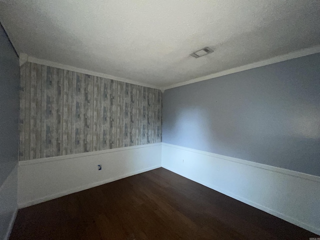 unfurnished room with dark wood-style flooring, crown molding, wallpapered walls, wainscoting, and a textured ceiling