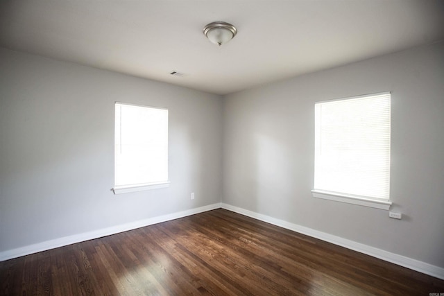 unfurnished room featuring baseboards and dark wood-type flooring