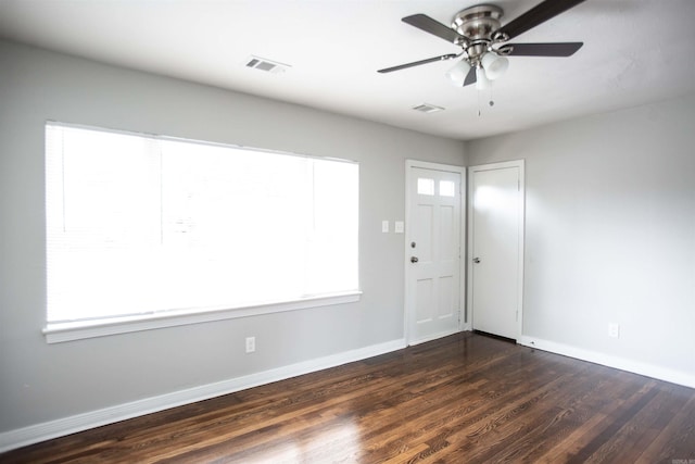 unfurnished room featuring dark wood-type flooring, a ceiling fan, and baseboards