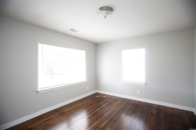 spare room featuring baseboards and dark wood-style flooring