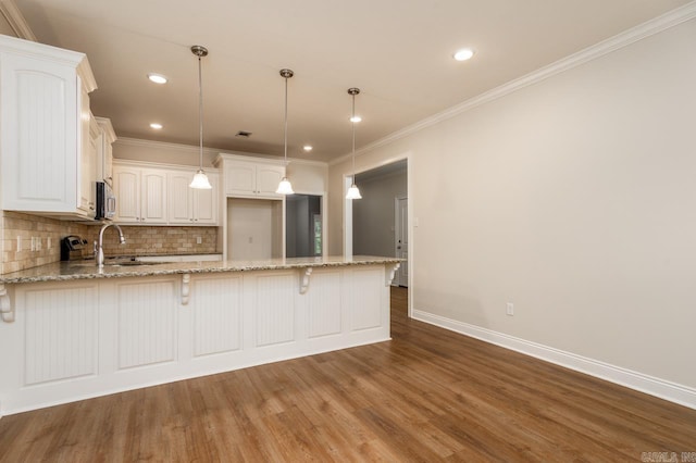 1710 Josh Dr, Conway, AR 72034 - kitchen with a sink, a peninsula, baseboards, light stone counters, and stainless steel microwave