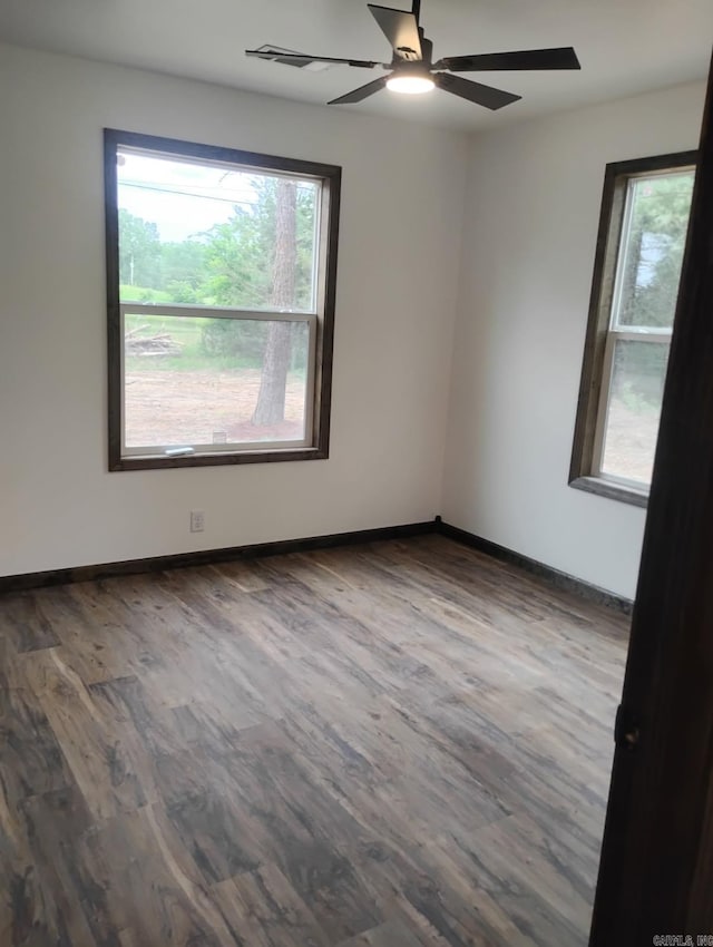 spare room with wood finished floors, a ceiling fan, and baseboards