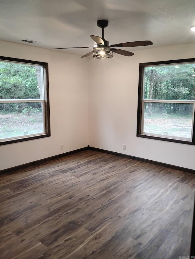 spare room with plenty of natural light, dark wood finished floors, and baseboards