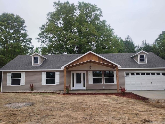 view of front of home with a garage, driveway, and a shingled roof