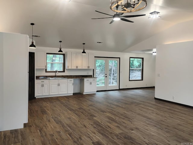 kitchen with dark countertops, ceiling fan, open floor plan, white cabinetry, and dark wood finished floors