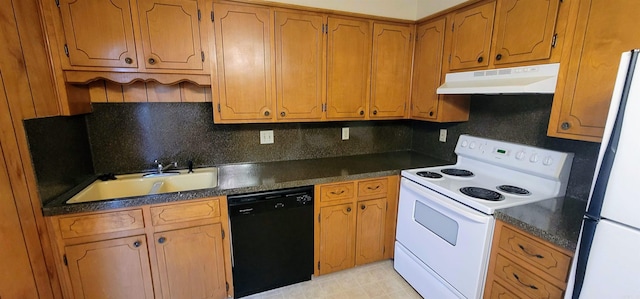 kitchen featuring white appliances, under cabinet range hood, a sink, and dark countertops
