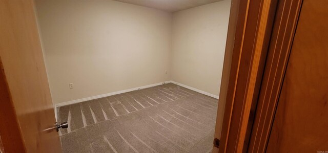 unfurnished room with dark carpet and baseboards