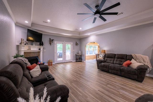 3407 Hemlock Cv, Benton, AR 72015 - living area with crown molding, light wood-type flooring, a ceiling fan, a tiled fireplace, and a tray ceiling