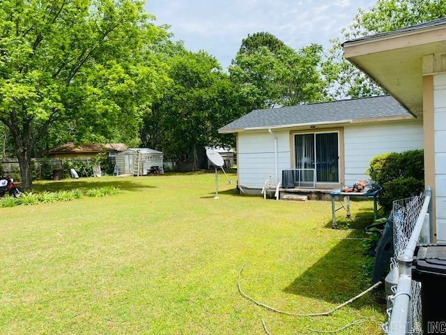 view of green lawn with a shed and an outdoor structure