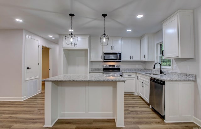 1114 Edgehill Dr, Benton, AR 72015 - kitchen with appliances with stainless steel finishes, a sink, white cabinets, light wood-style floors, and a kitchen island