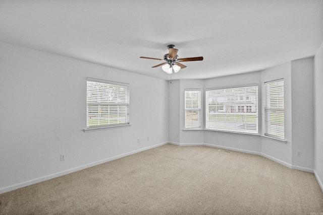 spare room featuring ceiling fan, light colored carpet, and baseboards
