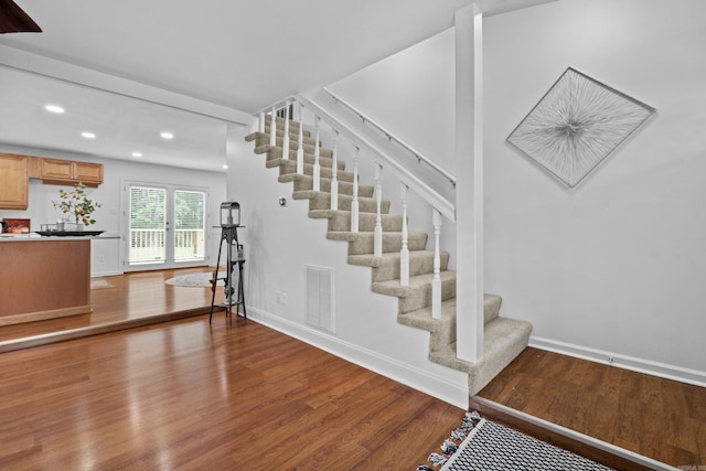 stairway with wood finished floors, recessed lighting, and baseboards