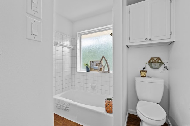 bathroom featuring wood finished floors, toilet, tub / shower combination, and baseboards