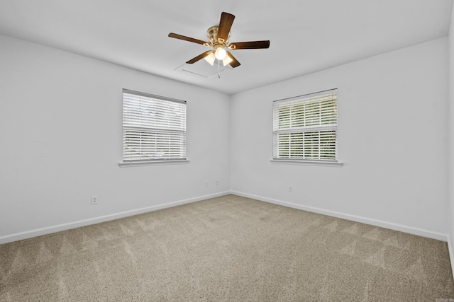 carpeted spare room featuring baseboards and ceiling fan