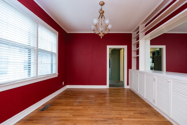 111 Thayer St, Little Rock, AR 72205 - unfurnished room with a chandelier, built in shelves, baseboards, light wood-style floors, and crown molding