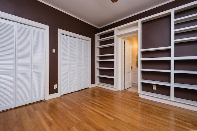 111 Thayer St, Little Rock, AR 72205 - unfurnished bedroom with wood finished floors, multiple closets, crown molding, and baseboards