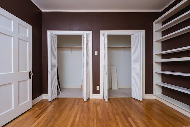 111 Thayer St, Little Rock, AR 72205 - unfurnished bedroom featuring multiple closets, light wood finished floors, ornamental molding, and baseboards