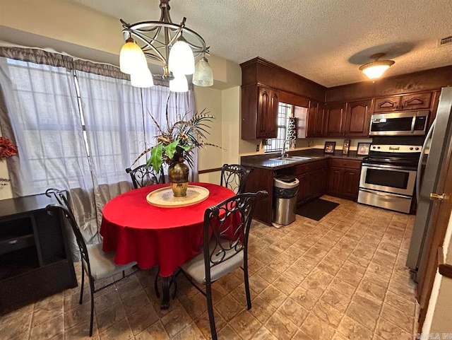 9314 Timber Valley Rd, Little Rock, AR 72204 - kitchen with appliances with stainless steel finishes, a sink, a textured ceiling, dark countertops, and a chandelier