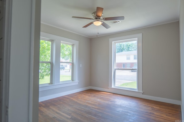 spare room featuring plenty of natural light, baseboards, wood finished floors, and ornamental molding