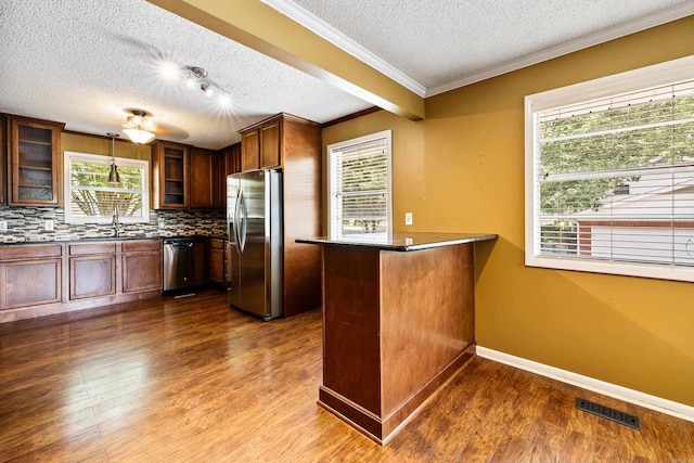 821 Mcadoo St, Little Rock, AR 72205 - kitchen featuring stainless steel appliances, a textured ceiling, backsplash, a peninsula, and glass insert cabinets
