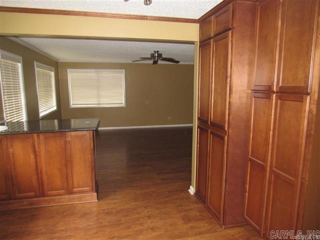 821 Mcadoo St, Little Rock, AR 72205 - kitchen with wood finished floors, brown cabinetry, ceiling fan, crown molding, and dark stone countertops