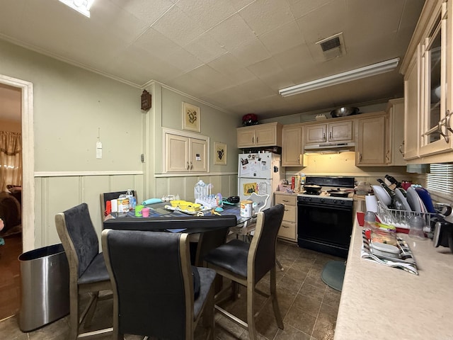 kitchen featuring range with gas stovetop, under cabinet range hood, light countertops, freestanding refrigerator, and ornamental molding