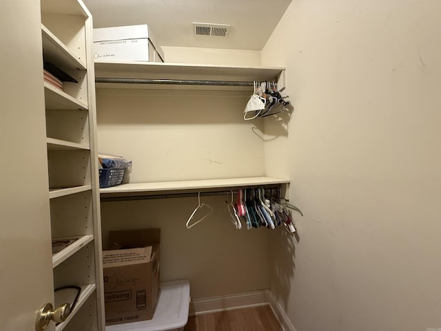 walk in closet with wood finished floors