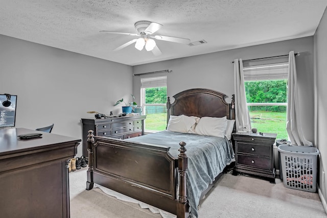 bedroom featuring light colored carpet, a textured ceiling, and a ceiling fan