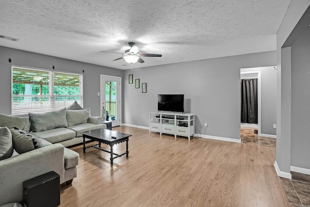 living room with ceiling fan, wood finished floors, a textured ceiling, and baseboards