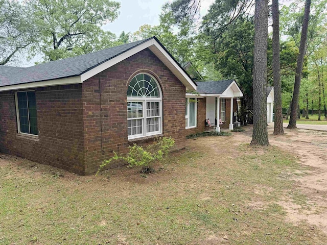 ranch-style home featuring brick siding, a shingled roof, central AC, and a front lawn