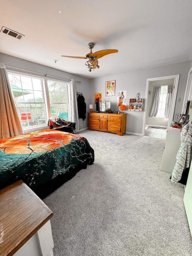 bedroom featuring light colored carpet, baseboards, a ceiling fan, and ensuite bathroom