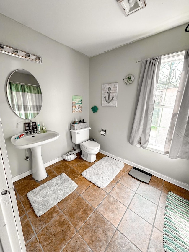 bathroom featuring tile patterned floors, toilet, baseboards, and a sink