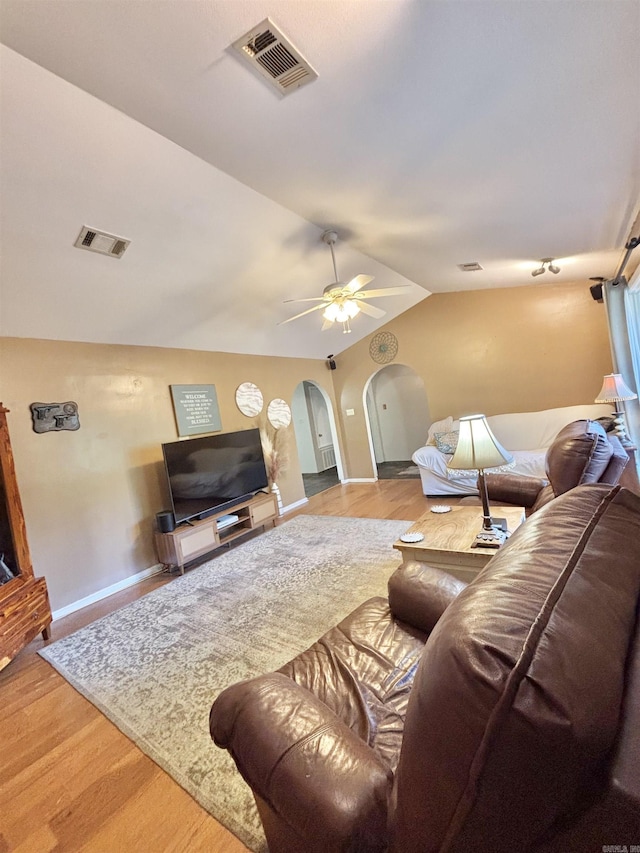 living room with arched walkways, lofted ceiling, wood finished floors, a ceiling fan, and baseboards