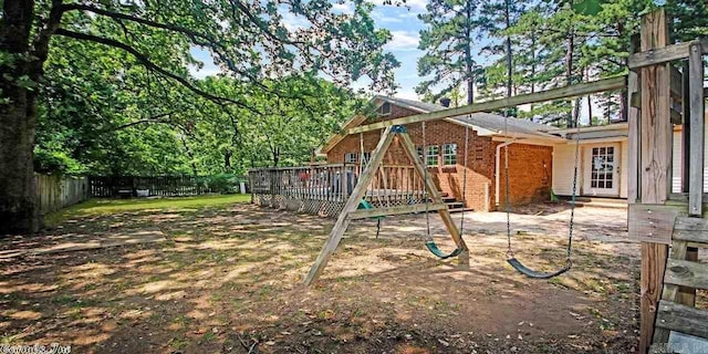 fenced backyard featuring a playground and a deck