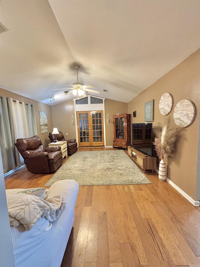 living room featuring light wood-style flooring, lofted ceiling, a ceiling fan, baseboards, and french doors