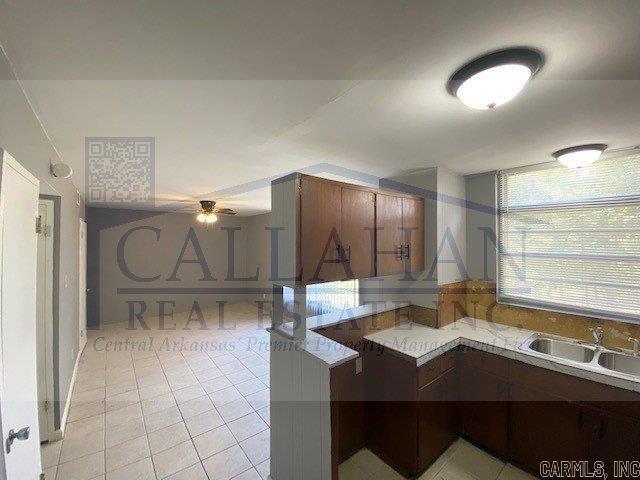110 Rim Rock Pl, North Little Rock, AR 72116 - kitchen with light tile patterned floors, a sink, light countertops, a peninsula, and ceiling fan
