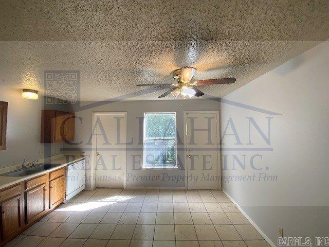 110 Rim Rock Pl, North Little Rock, AR 72116 - interior space featuring white dishwasher, a sink, a ceiling fan, brown cabinetry, and baseboards
