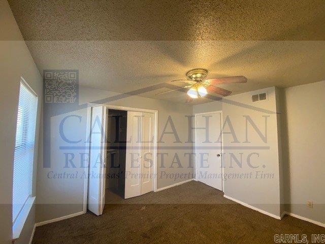 110 Rim Rock Pl, North Little Rock, AR 72116 - unfurnished bedroom with dark carpet, a textured ceiling, a ceiling fan, baseboards, and a closet