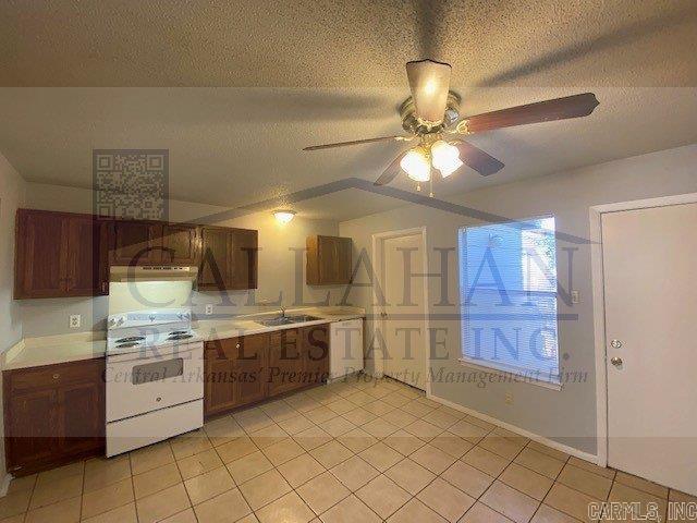 110 Rim Rock Pl, North Little Rock, AR 72116 - kitchen with white electric range, a sink, light tile patterned floors, ceiling fan, and under cabinet range hood